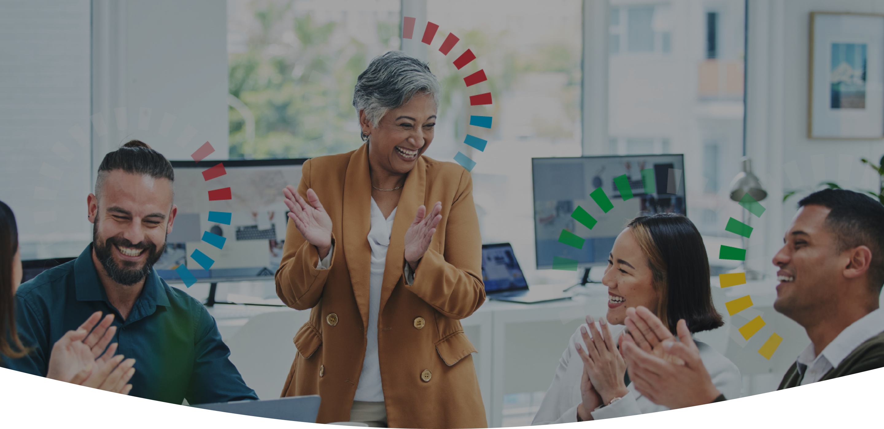 Background image of a team working together, with a manager standing up, the entire group is clapping and smiling.