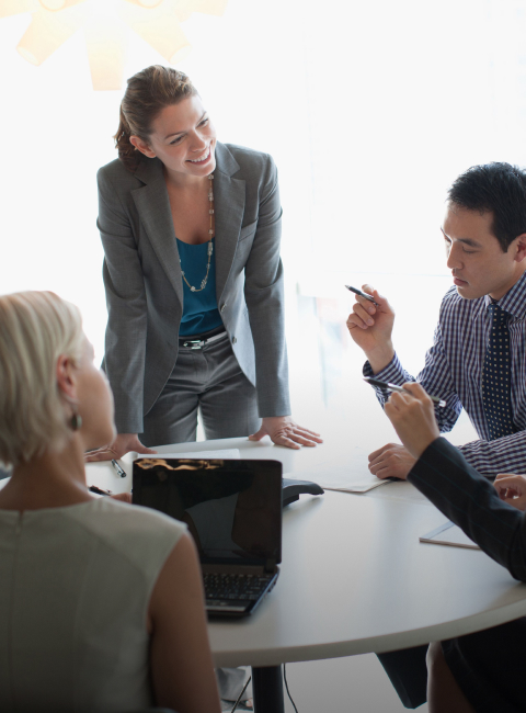A group of smiling coworkers working around a table. 