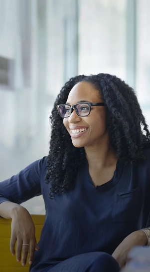 Close-up of a women smiling while sitting on a couch.