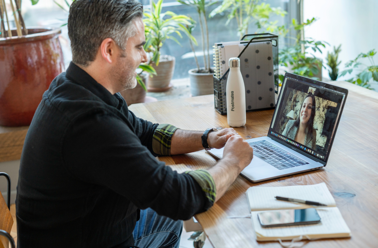 Man in a virtual meeting on a laptop at a desk.